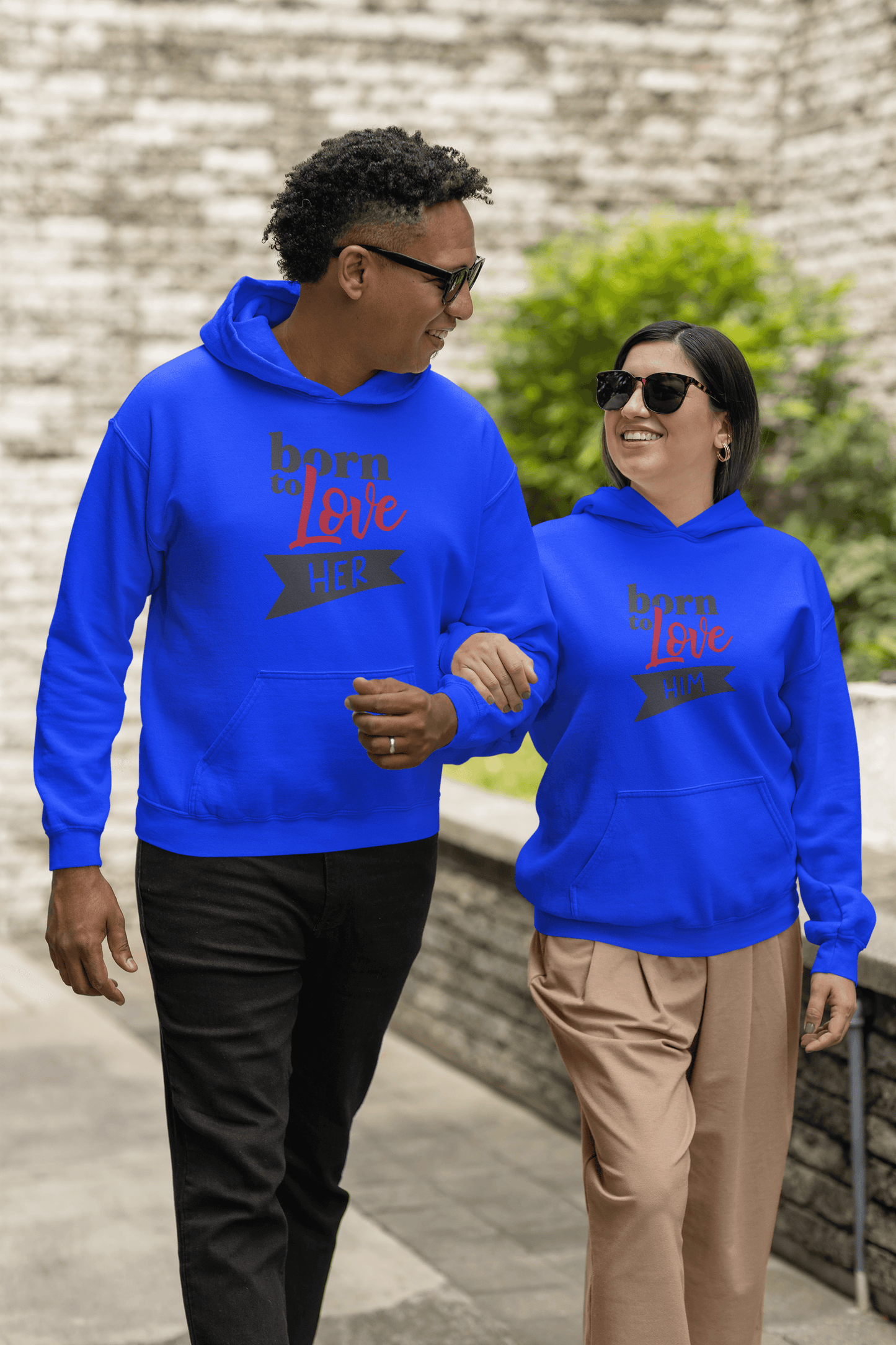 Couple wearing bright blue Born to Love hoodie set, walking together outdoors, showcasing stylish and cozy design.